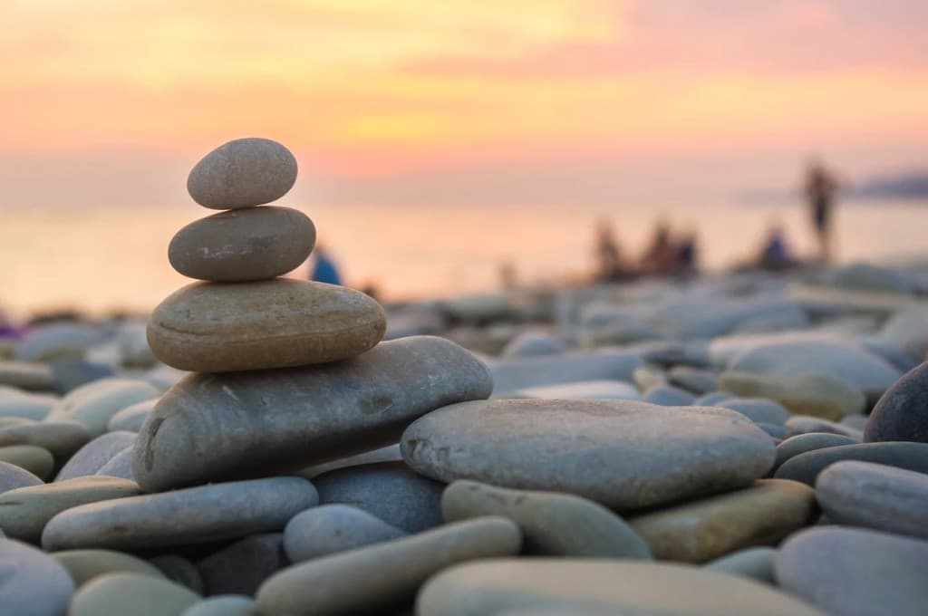 Pile de galets en équilibre sur une plage au coucher du soleil